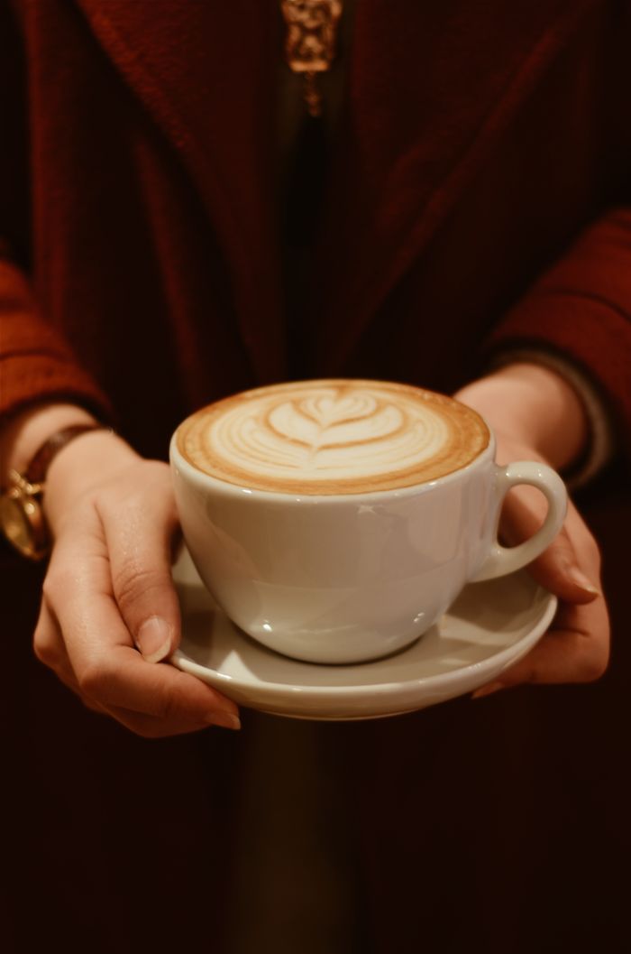 Warm close-up of a latte with art in a cozy setting, perfect for coffee lovers.
