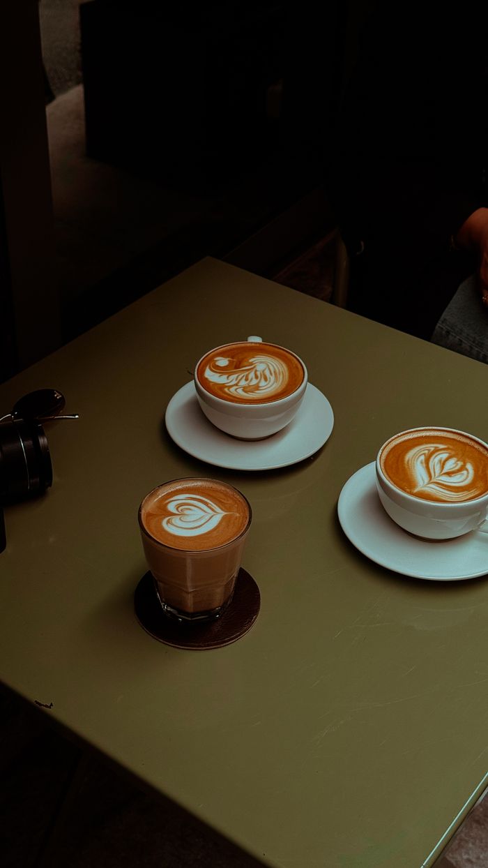 Three beautifully crafted latte and cappuccino cups showcasing coffee art designs.