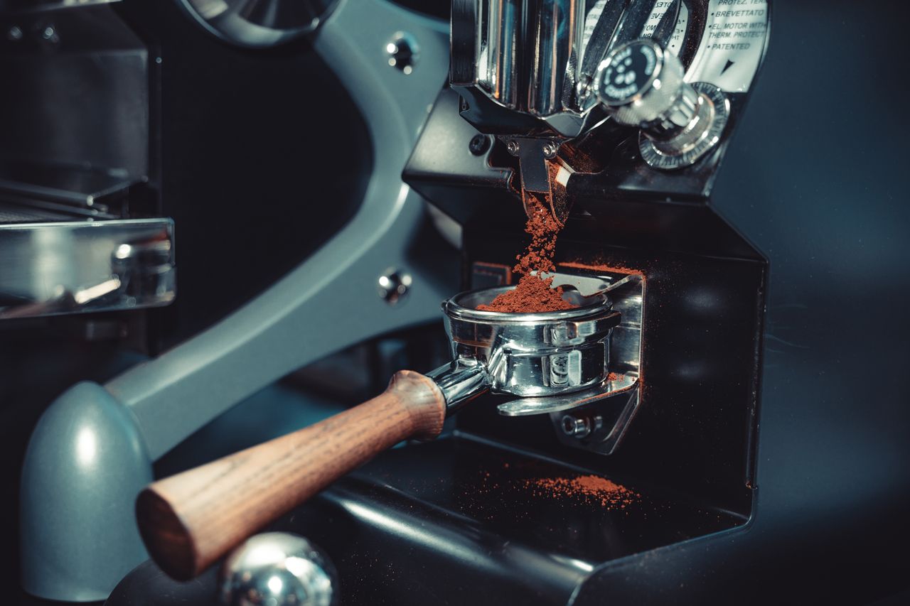 Close-up of a coffee machine portafilter collecting freshly ground coffee.