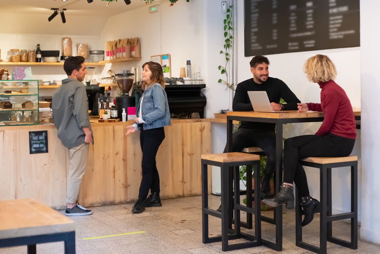 People interacting in a cozy Portuguese café, sharing conversations and drinks.